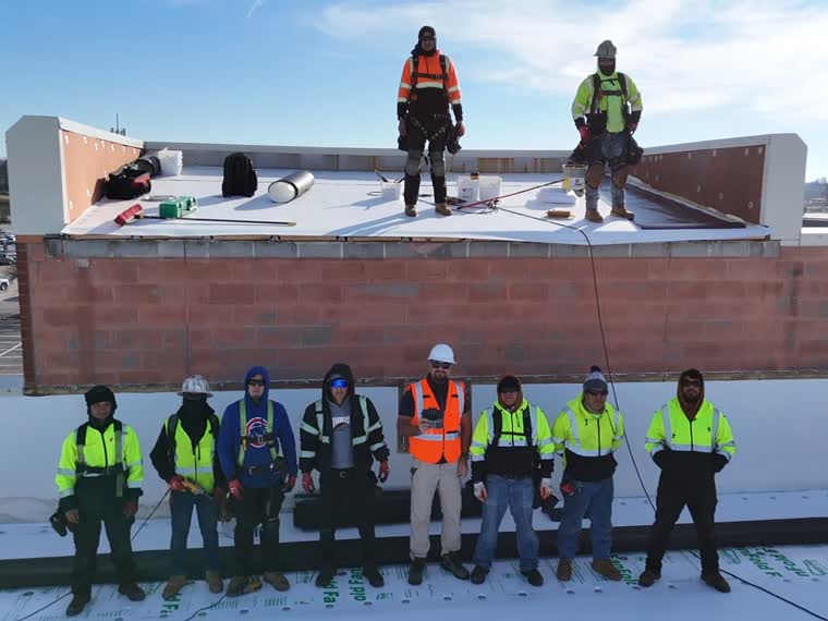 Crew on a completed roof section behind the parapet.