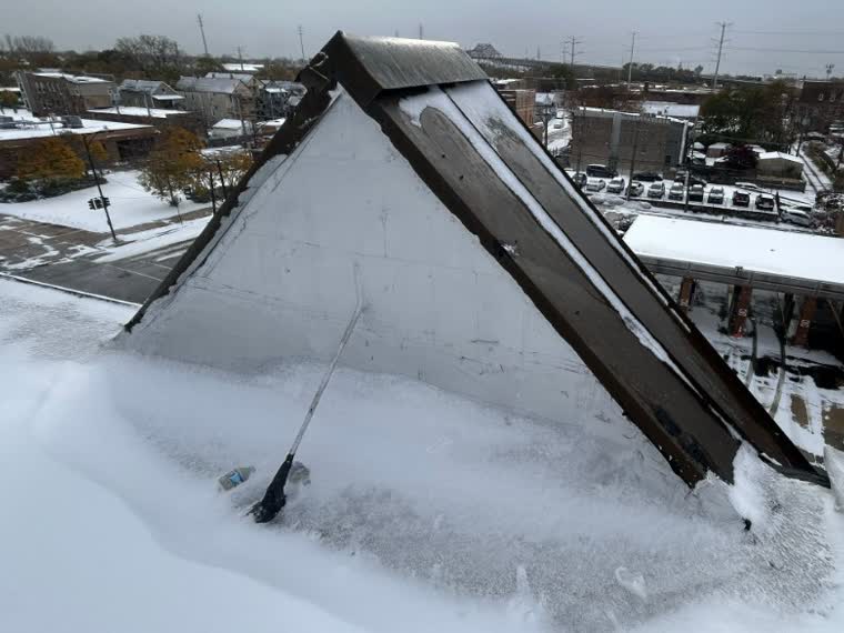 Snow load across a mansard roof section and the flat field behind it.