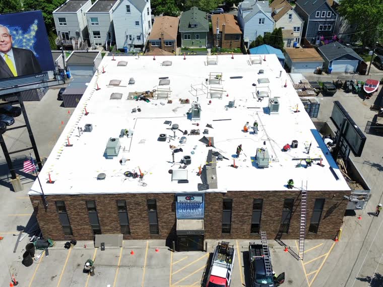 Completed roof over a masonry commercial building surrounded by rowhouses.