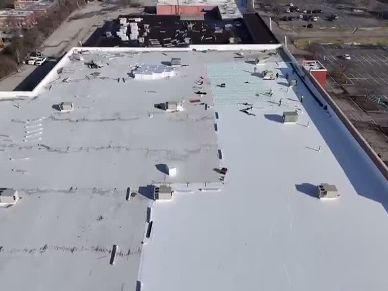 Aerial over a wide low-slope roof under bare winter canopy.