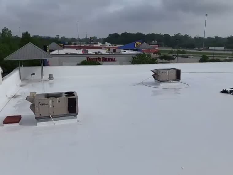 Close pass over a completed white roof and its equipment curbs.