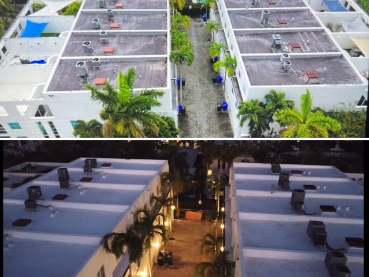 Aerial over a coastal commercial strip — reflective low-slope roofs running the block.
