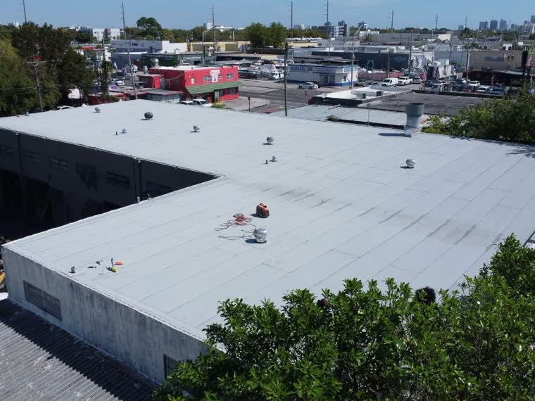 Large single-plane white roof, mechanical units set well inside the field.