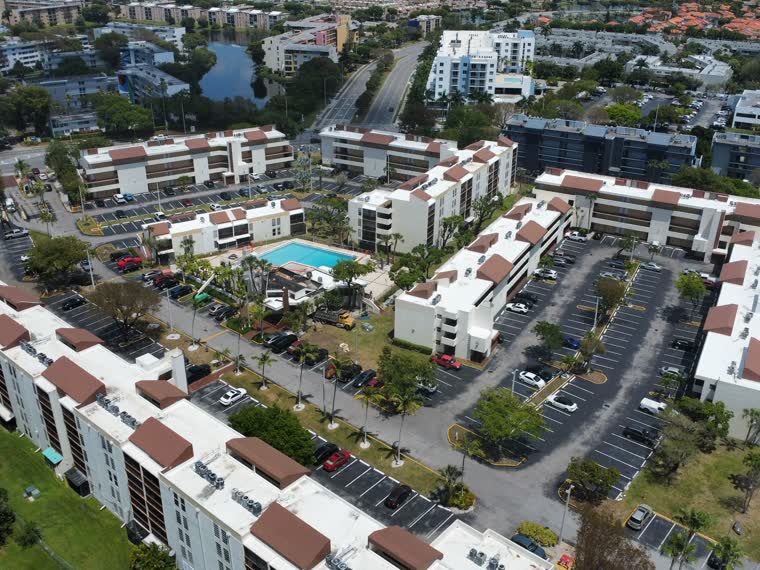 Aerial across a low-rise condominium community — reflective roofs over every building.
