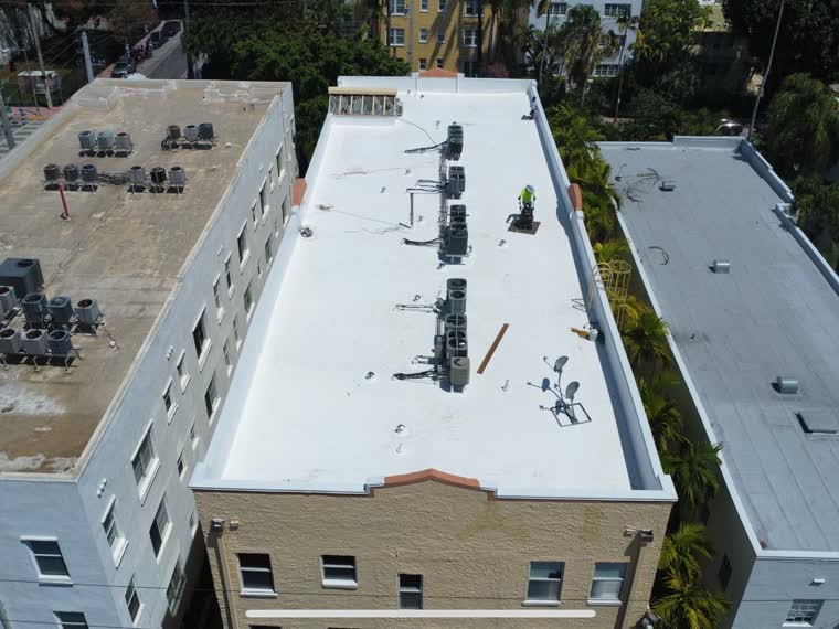 Completed roof on a mid-rise residential building, parapet and edge metal visible.