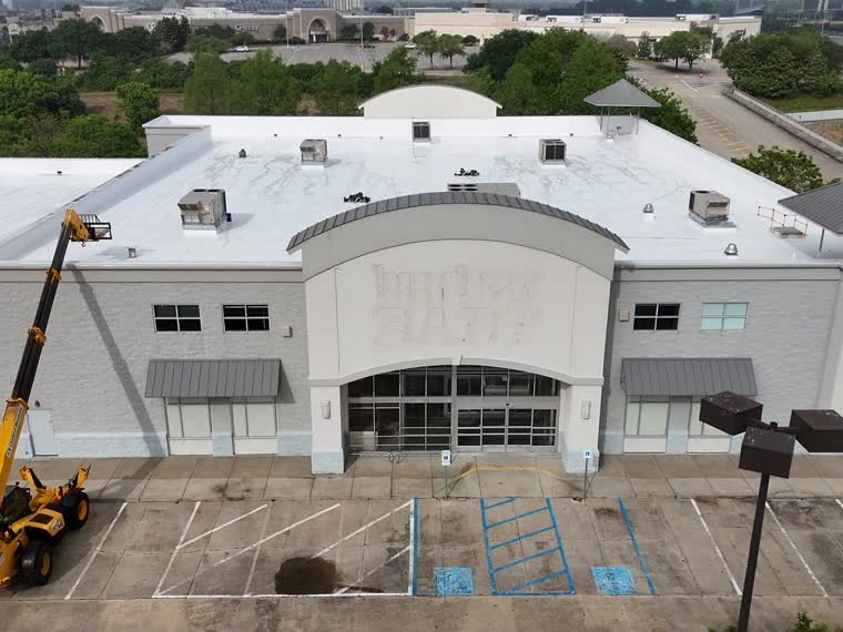 Curved-facade commercial building with a lift on site during roof work.