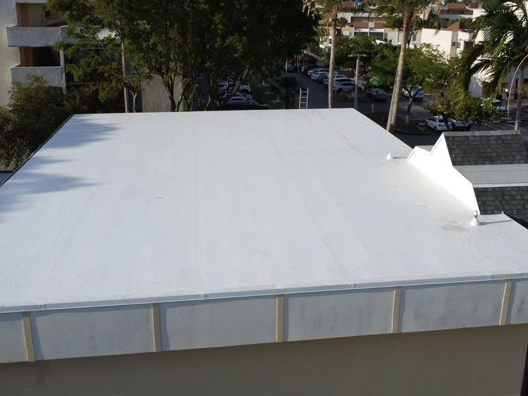 Close aerial on a finished reflective field, palm at the roof edge.
