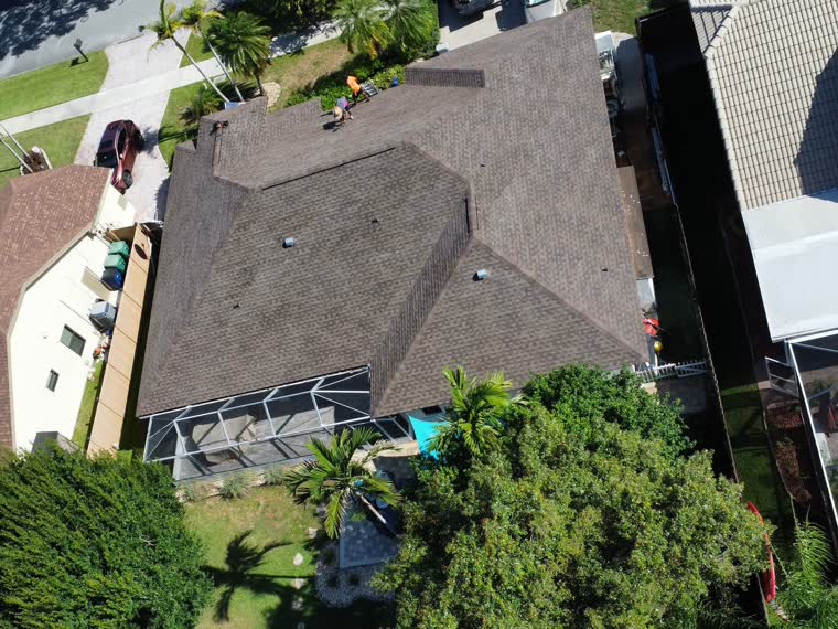 Residential property with a pitched roof and pool, mature tropical canopy.