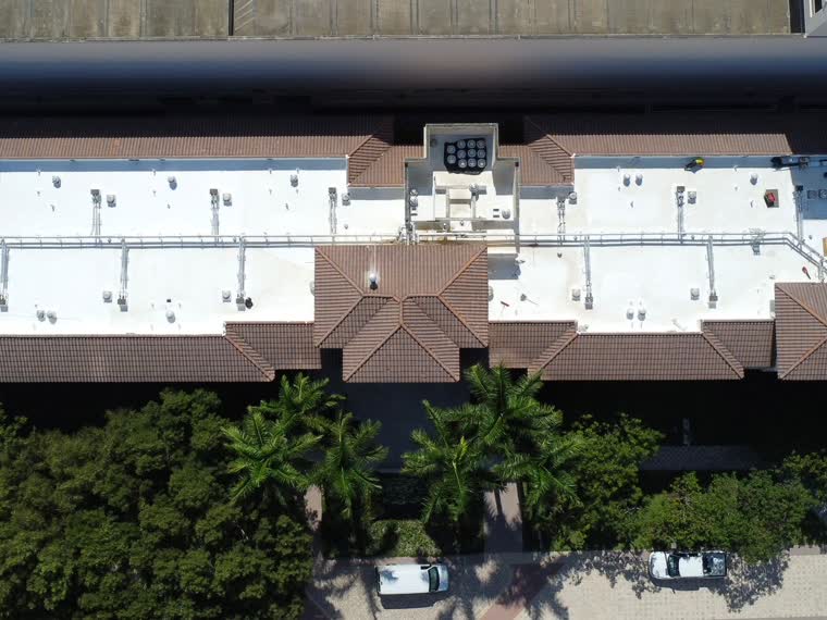 Reflective roof on a low-rise building among mature canopy.