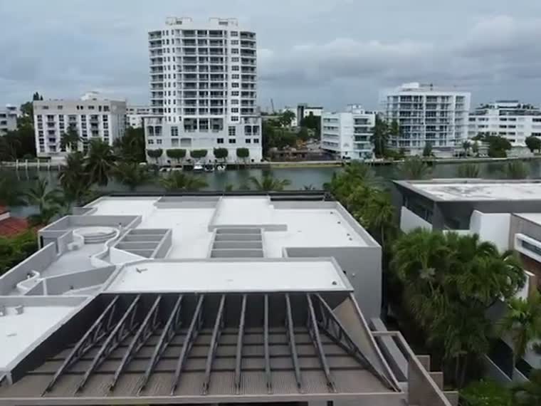 Flyover of mid-rise towers and the large low-slope roof beside them.
