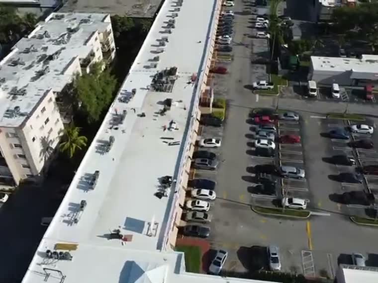 Aerial over a parking field and the commercial roofs adjoining it.
