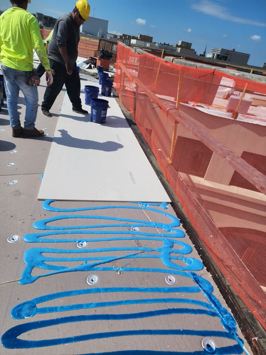 Close view of adhesive applied in a swirl pattern before setting roofing membrane