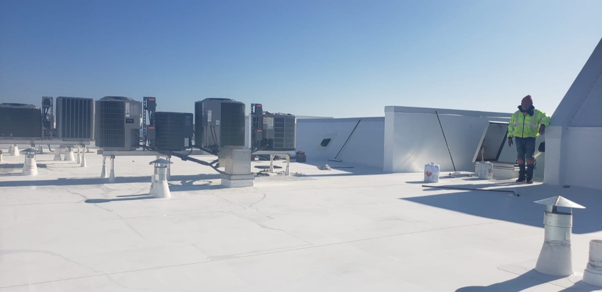 Rooftop HVAC units and equipment curbs on a finished white commercial roof